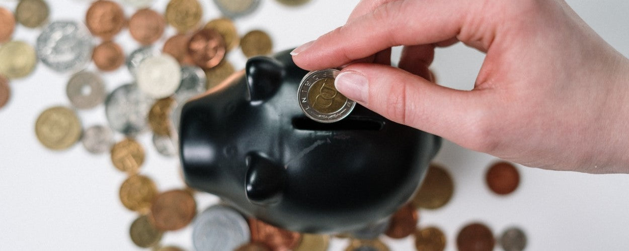 Putting coins into a black piggybank